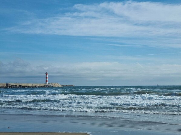 Un phare au bord de la mer, avec des vagues qui s’écrasent sur le rivage.