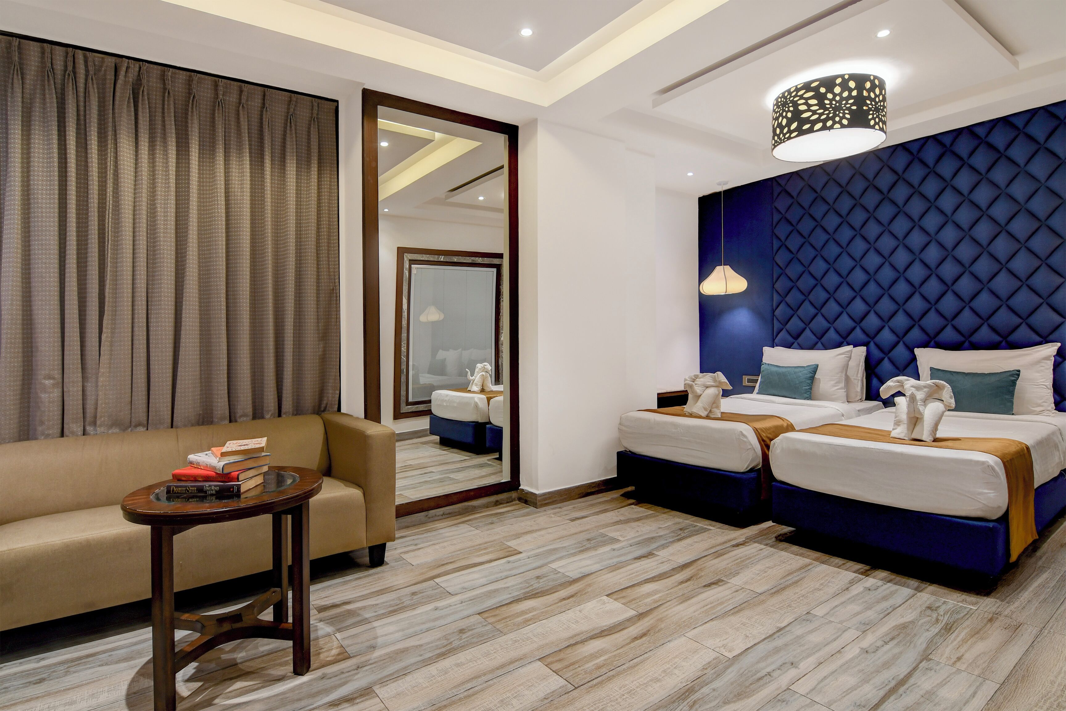 Une chambre d’hôtel avec un canapé, deux lits, une petite table et un miroir.