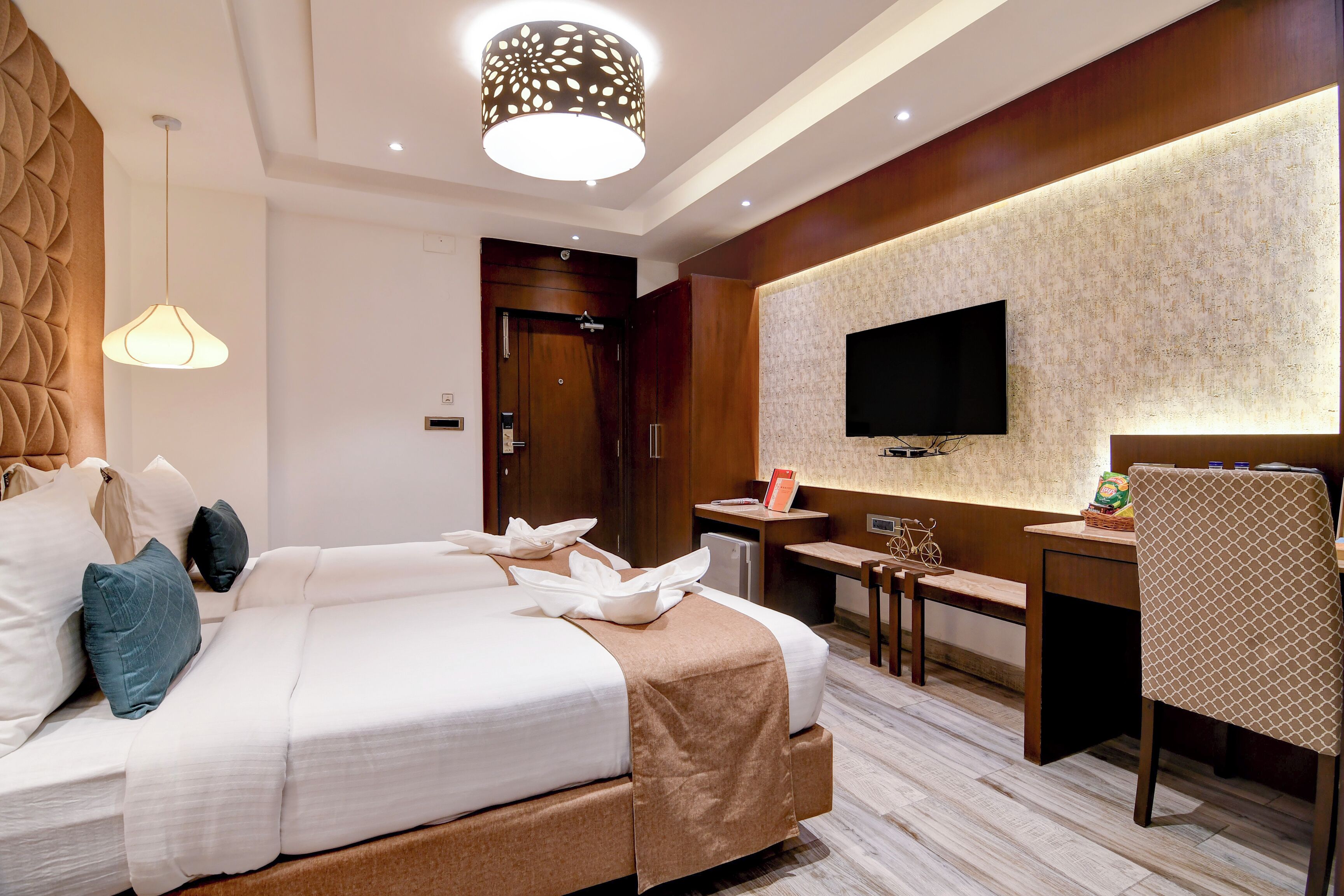 Habitación de hotel con una cama grande, un escritorio, un televisor y una lámpara moderna.