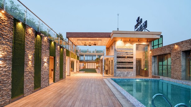 Uma área à beira da piscina com deck de madeira, paredes de pedra e piscina com cobertura de vidro.