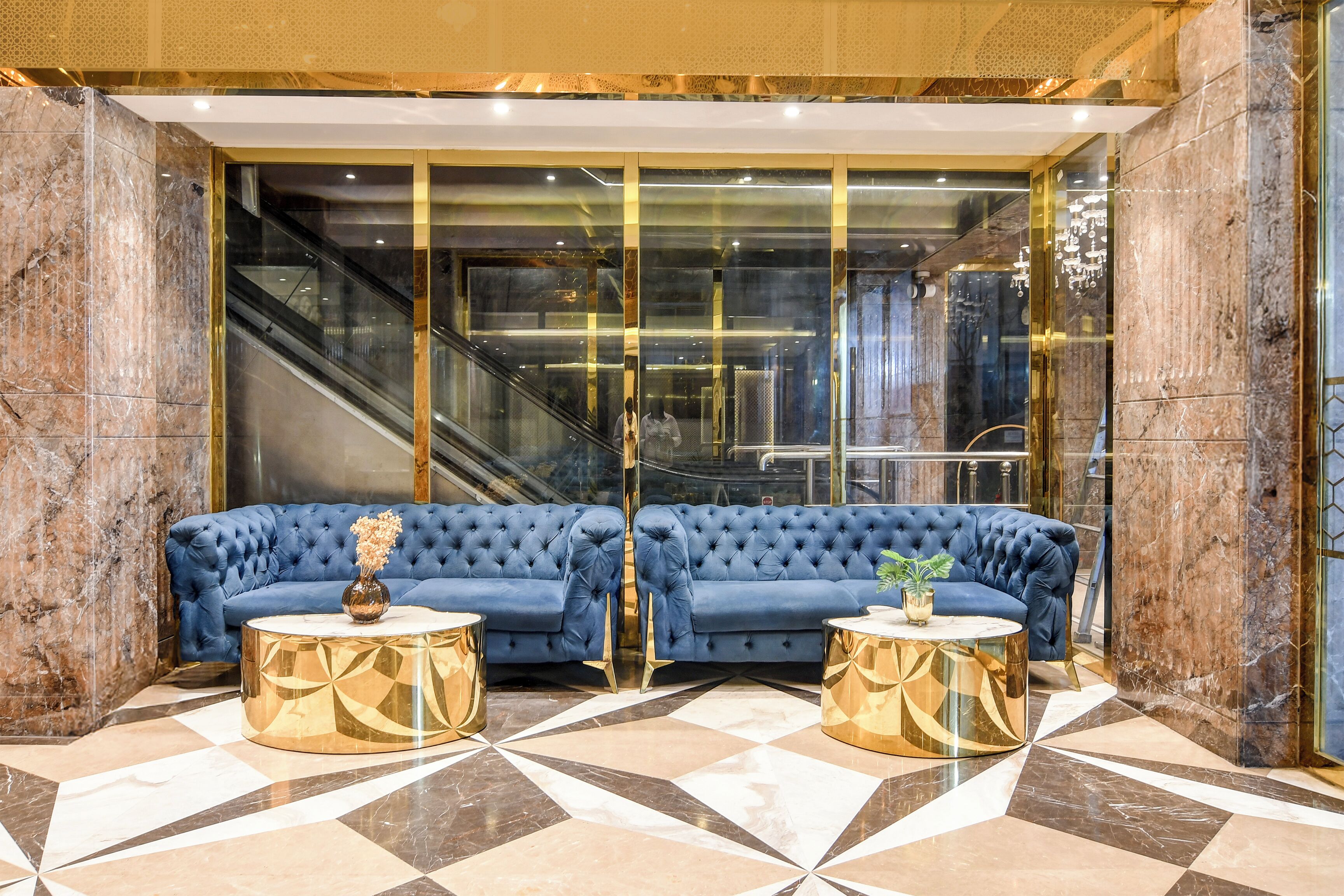 A lobby with a blue sofa, gold accents, and a checkered floor.