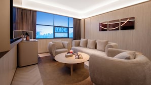 Een moderne hotelkamer met een groot raam, een bank, een bijzettafeltje en een klein bureau.