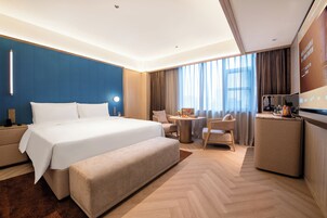 Una habitación de hotel moderna con una cama grande, un escritorio, una silla y una mesita.