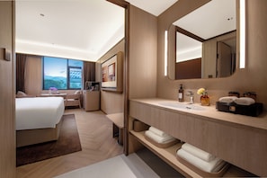 A modern hotel room with a large bed, a sofa, a desk, a bathroom with a sink, mirror, and toiletries. - Crystal Hotel Chongqing Railway Station (Chongqing)