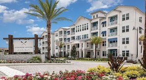 A multi-story hotel with balconies, a sign for 'Summer House at Lake Apalachicola', and a landscaped garden with flowers. - Landing | Stylish 3BD, Clubhouse, Gym (Apopka)