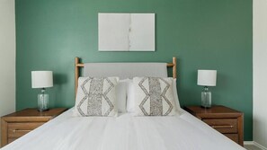 A bed with a wooden headboard, two nightstands with lamps, and a green wall. - Landing | Spectacular 2BD in Copperfield (Cypress)