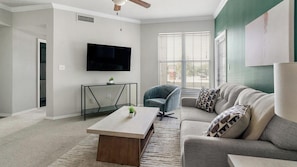 A living room with a flat-screen TV, a glass coffee table, a sofa, and a chair. - Landing | Spectacular 2BD in Copperfield (Cypress)