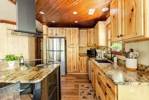 A kitchen with wooden cabinets, a stainless steel refrigerator, granite countertops, and a wooden ceiling. - Waterfront Cabin with Waterfall View, Private Firepit & Hiking Trails, WiFi (Robbinsville)