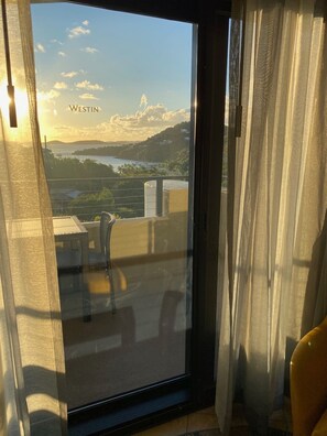 Ein Fenster mit Blick auf eine Küstenlandschaft, darunter Hügel und ein Gewässer.