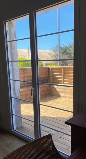 Ein Zimmer mit einer Schiebetür und Zugang zu einer Terrasse mit Holzboden und Holzumzäunung.