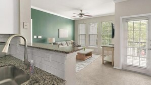 A kitchen with a granite countertop, a ceiling fan, and a view through the glass door. - Landing | Stylish 1BD in Copperfield (Cypress)