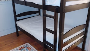 Ein Etagenbett mit Holzrahmen, weißer Bettwäsche und einem gemusterten Teppich auf Holzboden.