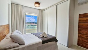 A hotel room with a bed, a view of a tennis court, and a wooden wall. - COARM0114 - Acqua Vert Loft Residence (Salvador)