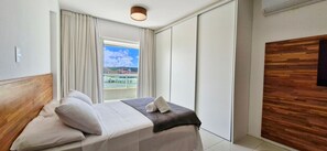 A hotel room with a bed, a view of a tennis court, and a wooden wall.