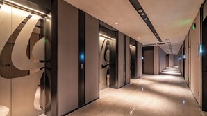 A modern hotel corridor with elevators, a marble floor, and a clean, minimalist design. - Orange Crystal Hongyadong Hotel (Chongqing)