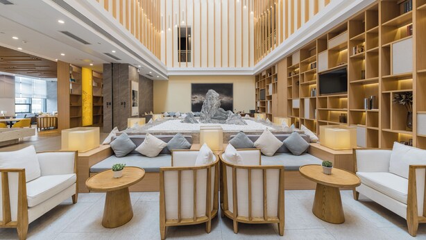 A spacious lobby with a central seating area, a large TV screen, and a bookshelf. - Orange Crystal Hongyadong Hotel (Chongqing)