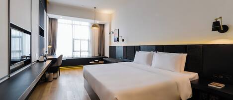 A modern hotel room with a large bed, a desk, and a window with curtains.