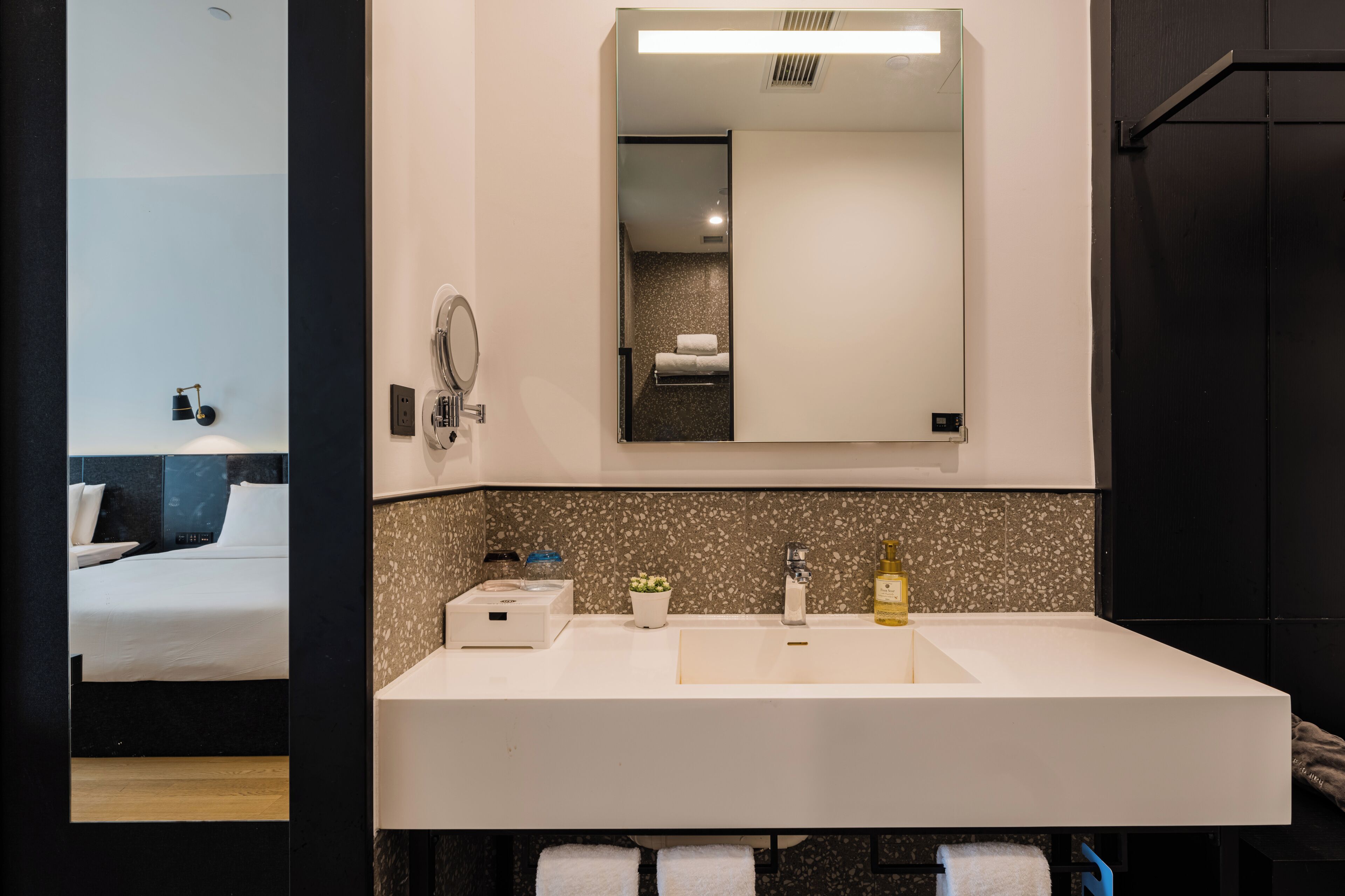 Un baño moderno con un espejo grande, un lavabo blanco y un perchero para toallas.
