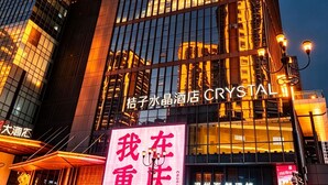 A modern hotel building with illuminated signage, large windows, and a prominent 'CRYSTAL' sign. - Orange Crystal Hongyadong Hotel (Chongqing)