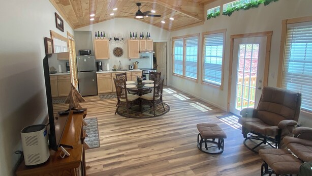 A spacious kitchen with wooden cabinets, a dining area with a round table and chairs, and large windows with blinds. - Hudlow Hideaway…A perfect and secluded couple’s getaway with hot tub! (Union Mills)