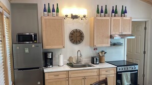 A kitchen with wooden cabinets, a microwave, a coffee maker, a toaster, and a stove. - Hudlow Hideaway…A perfect and secluded couple’s getaway with hot tub! (Union Mills)