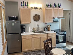 Una cocina con gabinetes de madera, microondas, cafetera, tostadora y estufa.