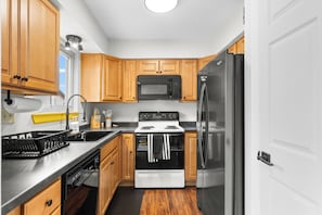 Une cuisine compacte avec des meubles en bois, un réfrigérateur en acier inoxydable, un four à micro-ondes et une cuisinière.