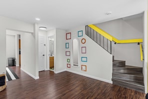 Un intérieur moderne comprenant un escalier, un couloir et une porte donnant sur une cuisine.