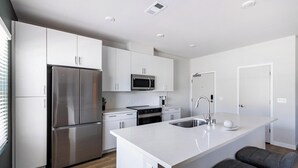 A modern kitchen with stainless steel appliances, white cabinetry, and a central island with seating. - Landing | Stunning 1BD, Clubhouse, Courtyard (Santa Rosa)