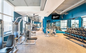 A gym with various exercise equipment, a bench, and dumbbells. - Landing | Stylish 2BD in Downtown (Savannah)