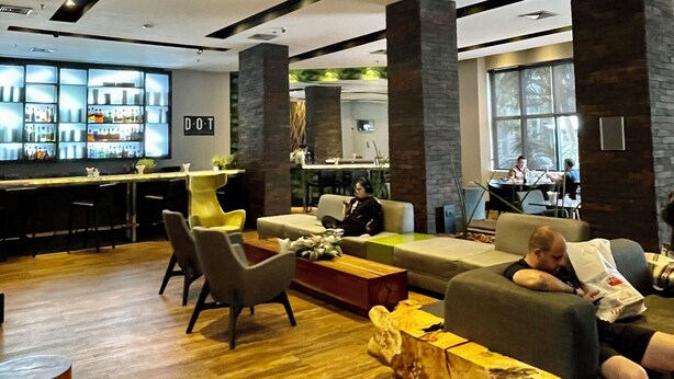 Een moderne lobby met een bar, zitplaatsen en een zichtbare keuken op de achtergrond.