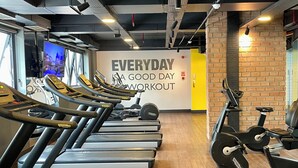 Een sportschool met loopbanden, hometrainers en een motiverende muur.