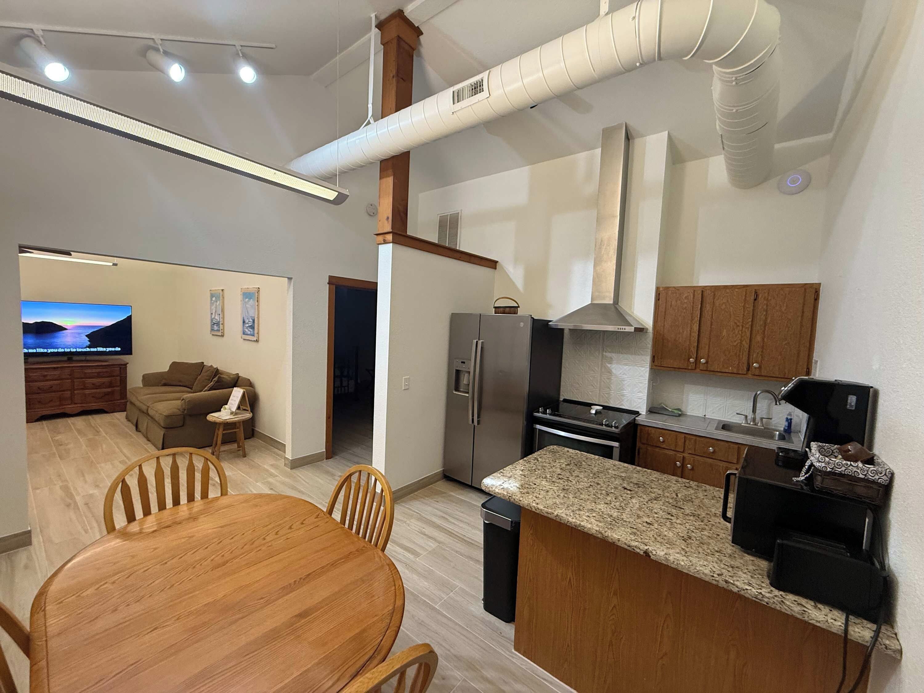 A modern kitchen with a central island, stainless steel appliances, and a dining area with a wooden table and chairs.