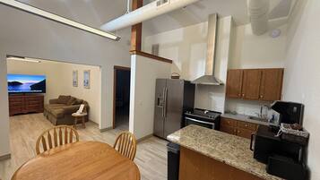 A modern kitchen with a central island, stainless steel appliances, and a dining area with a wooden table and chairs.