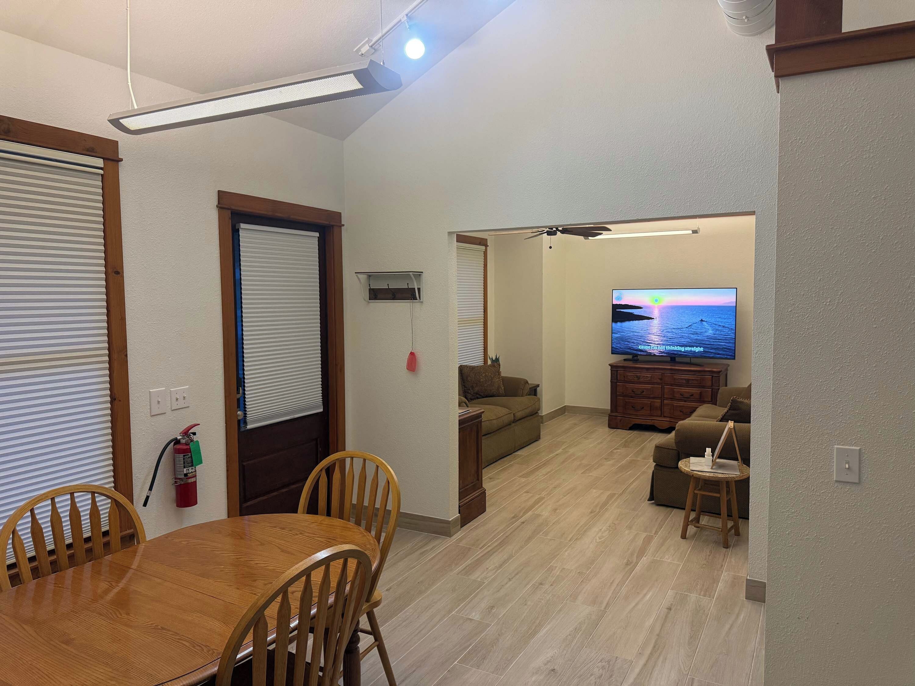 A living room with a flat-screen TV, wooden furniture, and a ceiling fan.