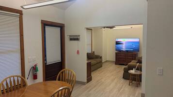 A living room with a flat-screen TV, wooden furniture, and a ceiling fan.