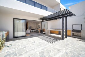 Eine moderne Außenpatio mit Pergola, Grillplatz und Blick in den angrenzenden Wohnbereich.