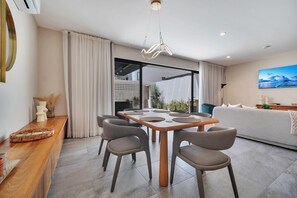 Ein modernes Wohnzimmer mit Essbereich, großen Fenstern und Blick ins Freie.