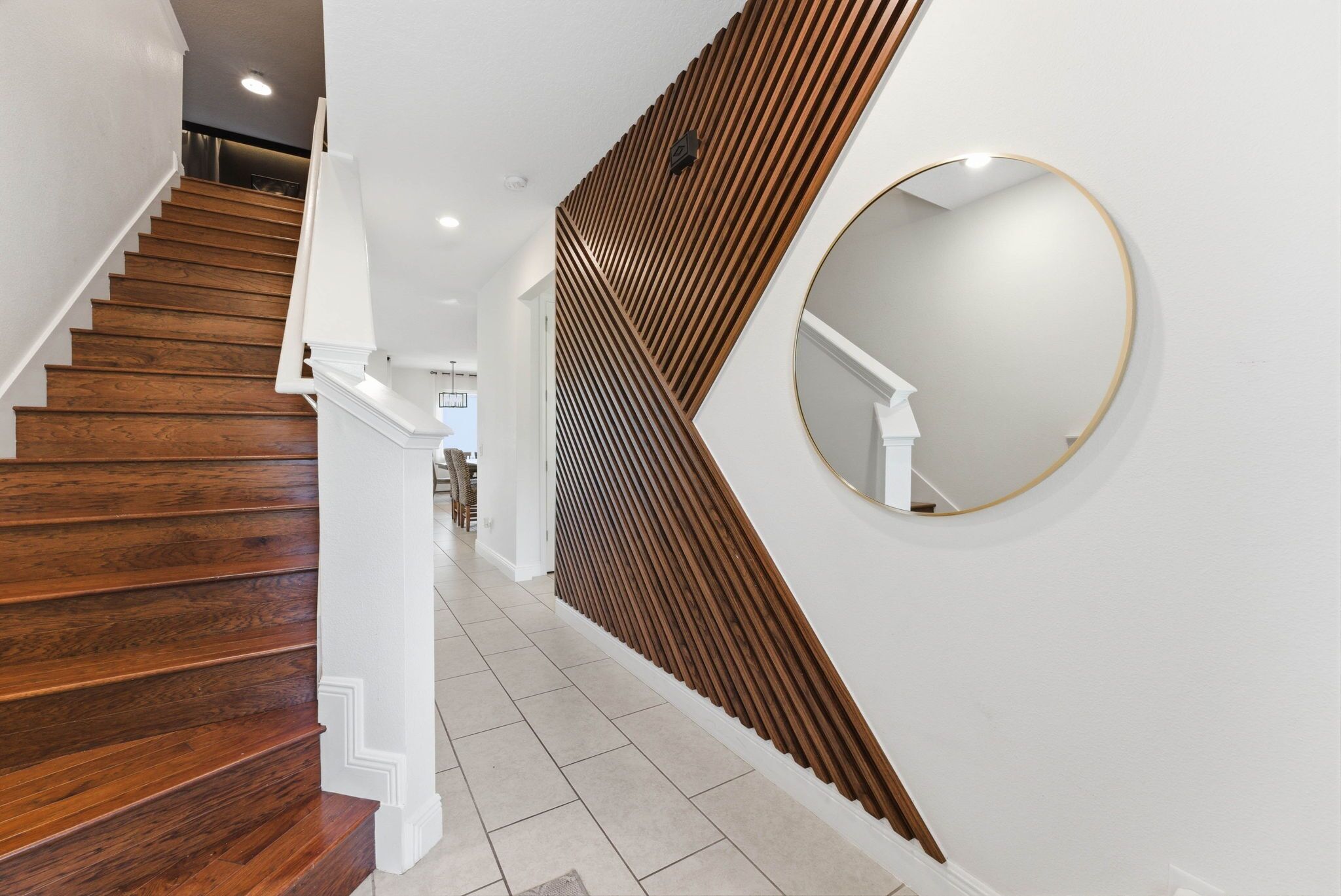Un escalier avec des marches en bois, des rampes blanches et un miroir fixé au mur.