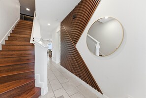Eine Treppe mit Holzsitzstufen, weißen Geländern und einem an der Wand befestigten Spiegel.