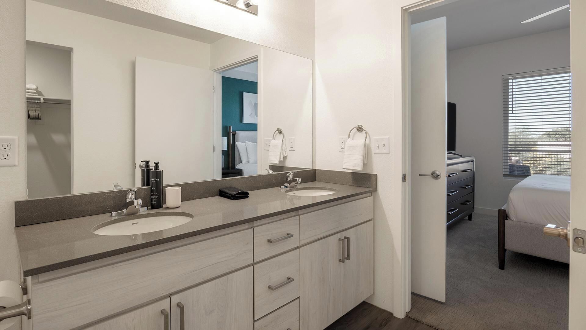 Un bagno moderno con due lavabi, uno specchio grande e un cabina armadio.