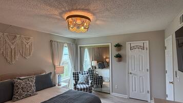 Quarto com cama, cadeira, porta e espelho.