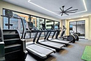 Ein modernes Fitnessstudio mit Laufbändern, Ergometer und einem Deckenventilator.