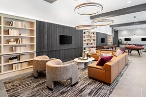 Ein modernes Wohnzimmer mit einer Couch, Sesseln, einem Couchtisch und Bücherregalen.