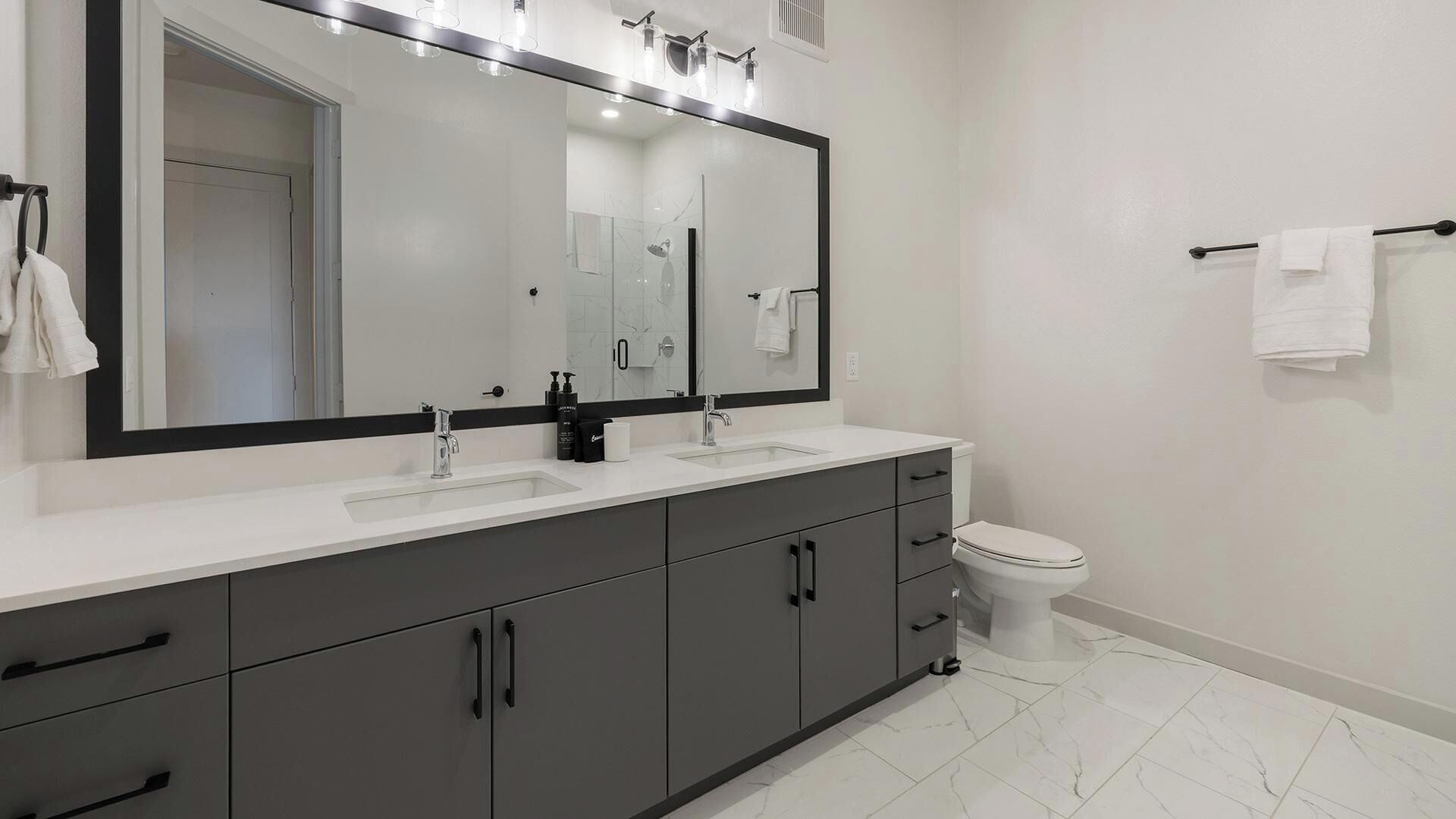 Une salle de bain moderne avec un meuble-lavabo à deux vasques, des toilettes et un porte-serviettes.