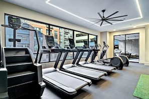 Ein modernes Fitnessstudio mit Laufbändern, Ergometer und einem Deckenventilator.