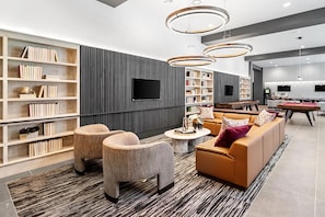 Ein modernes Wohnzimmer mit einer Couch, Sesseln, einem Couchtisch und Bücherregalen.