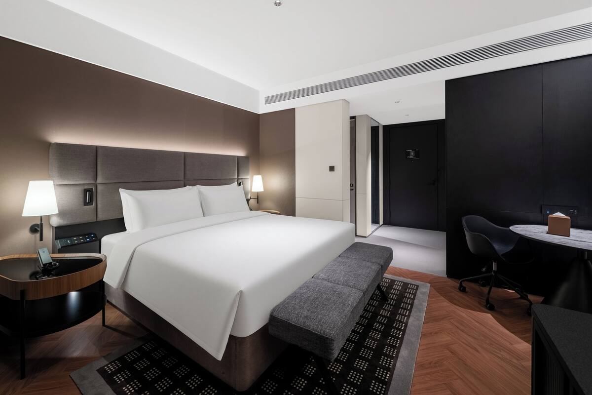 Ein modernes Hotelzimmer mit einem Bett, Nachttischen, einem Schreibtisch und einem Stuhl.