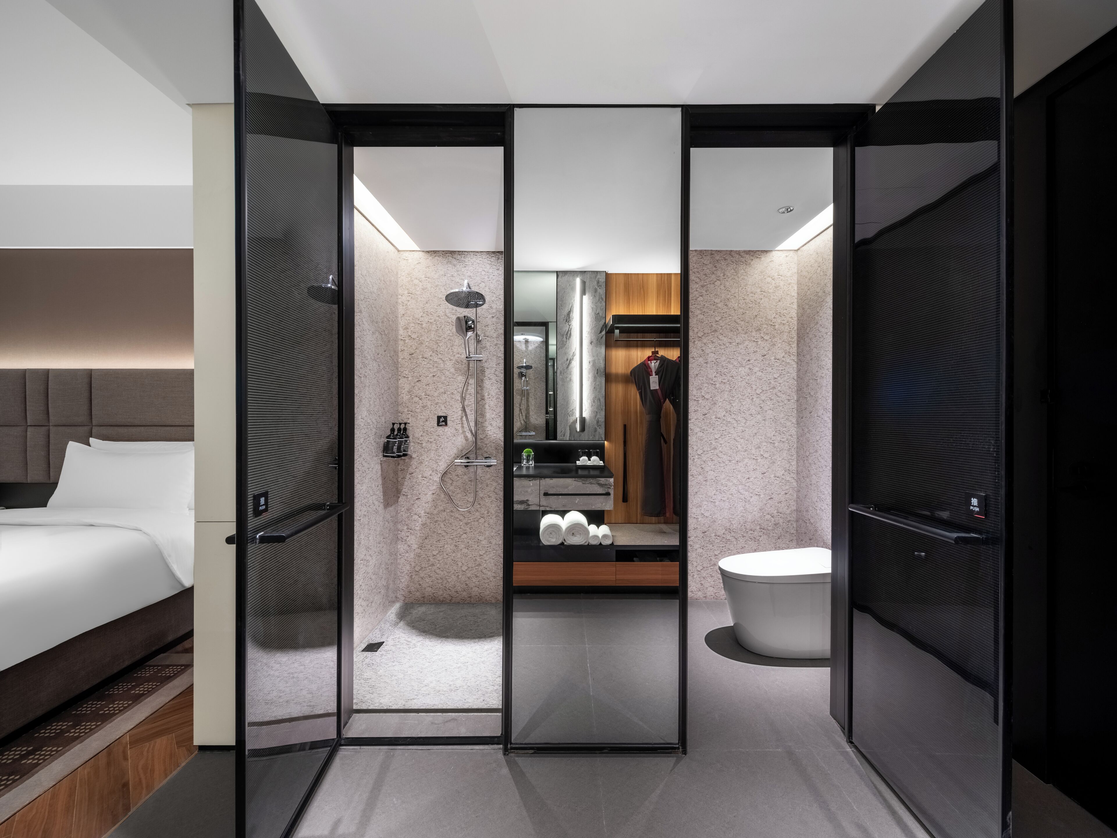 Een moderne hotelkamer met een bed, douche, toilet en spiegel.