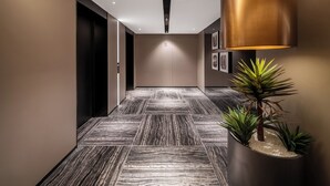 A modern hallway with a patterned floor, a wall-mounted lamp, and a potted plant. - Intercity Hotel Guanyinqiao Chongqing (Chongqing)